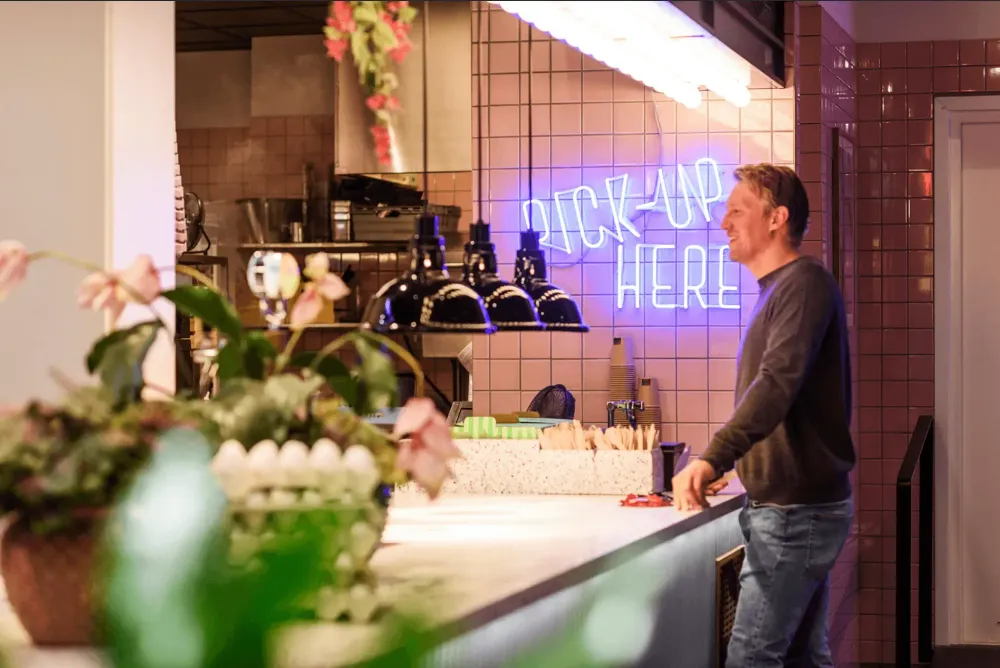 A man waiting to pick up food in a restaurant