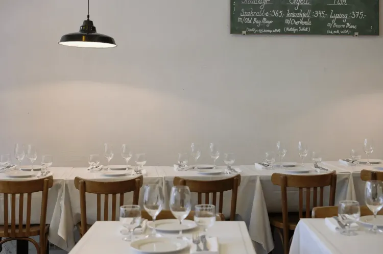 Tables in a restaurant with white cloth with plates and glasses