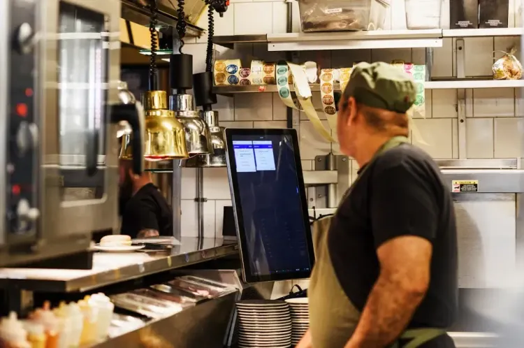 A chef in the kitchen looking at the digital kitchen screen