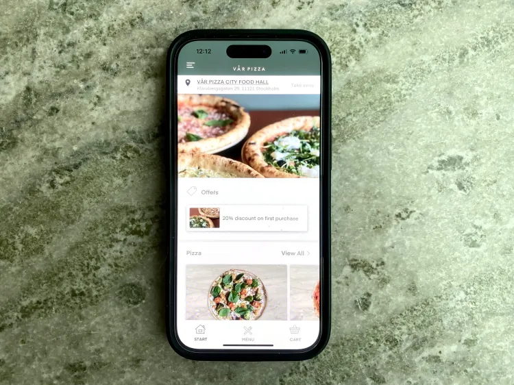 Phone on a table showing Vår pizza online ordering
