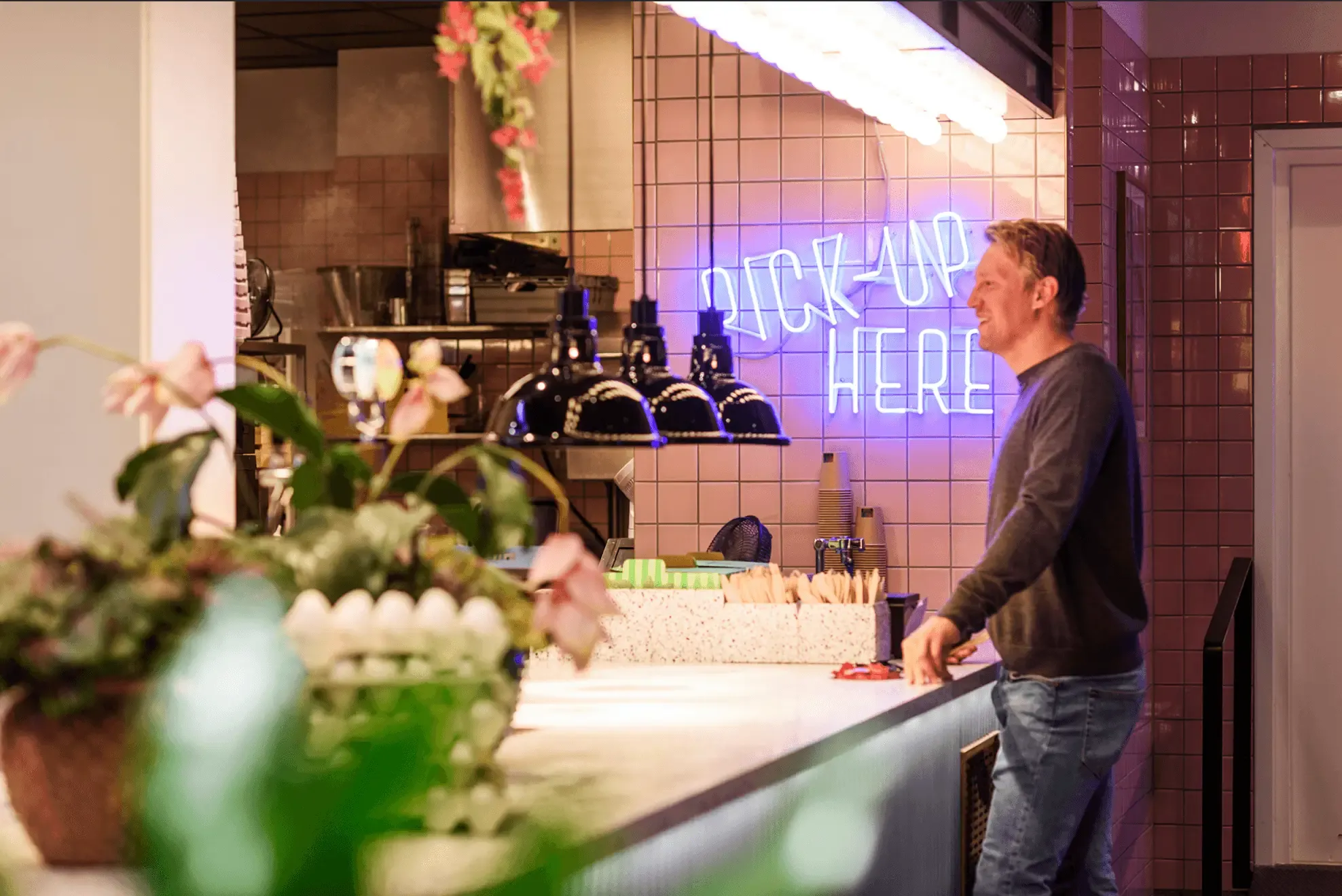 A man waiting to pick up food in a restaurant