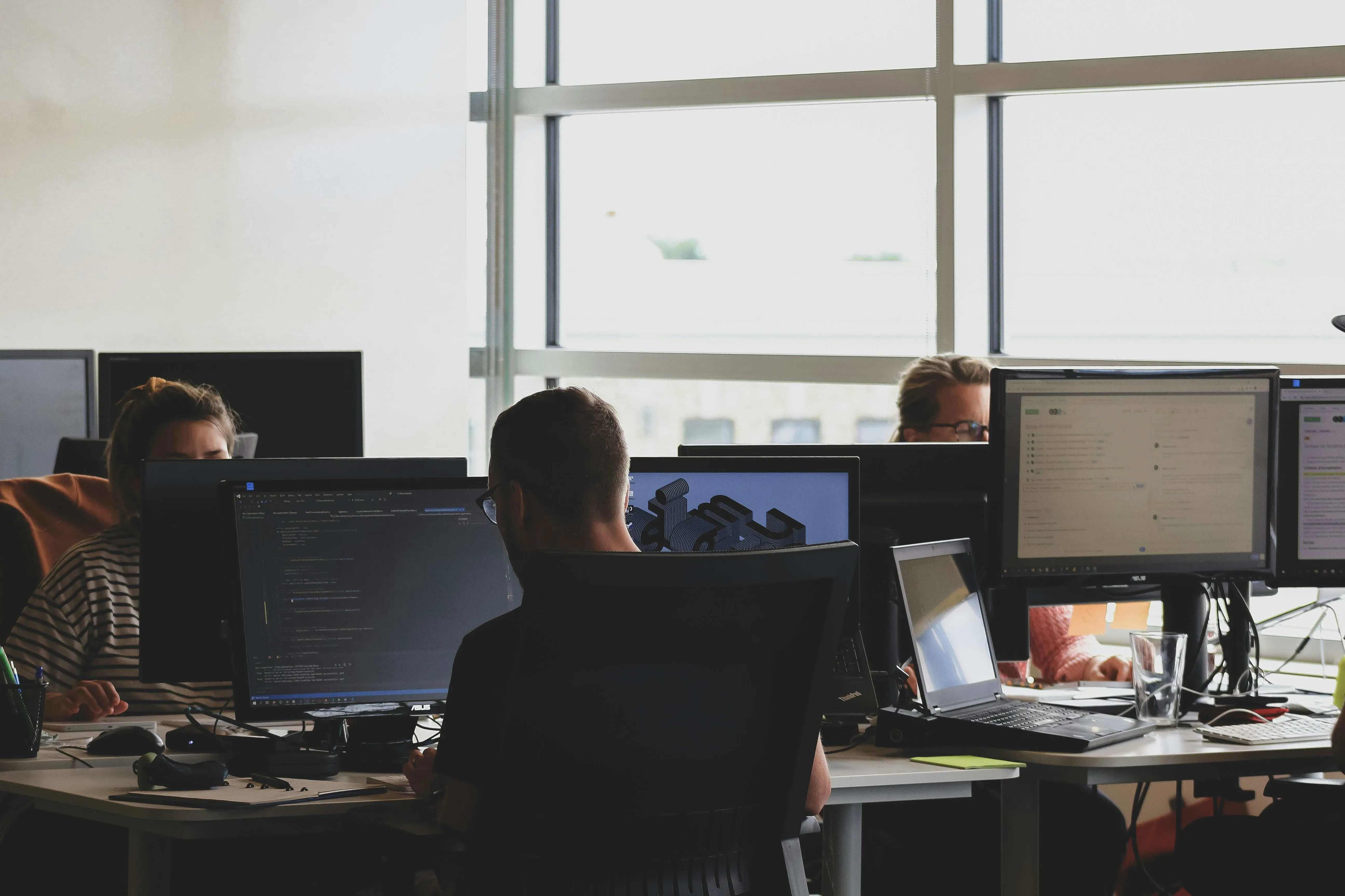 People sitting in an office with a lot of monitors